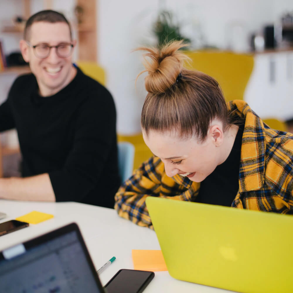 A man and a woman smiling at a desk