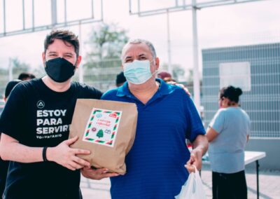 A younger male and an older male with masks on holding a box together