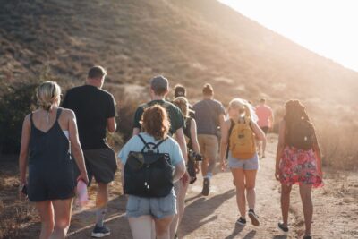 A group walking down a trail by a hill