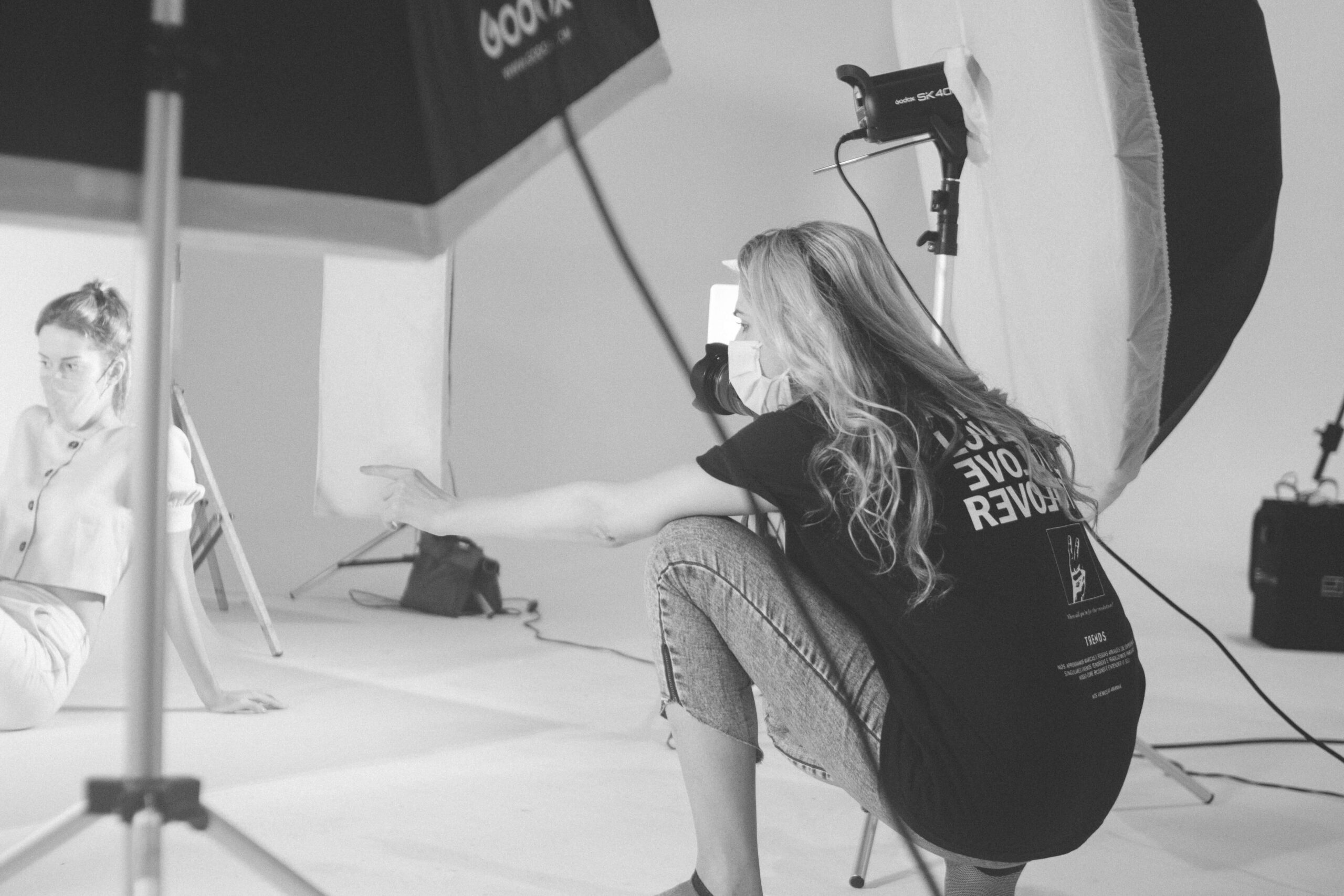 A woman squatting to capture a photo in a studio