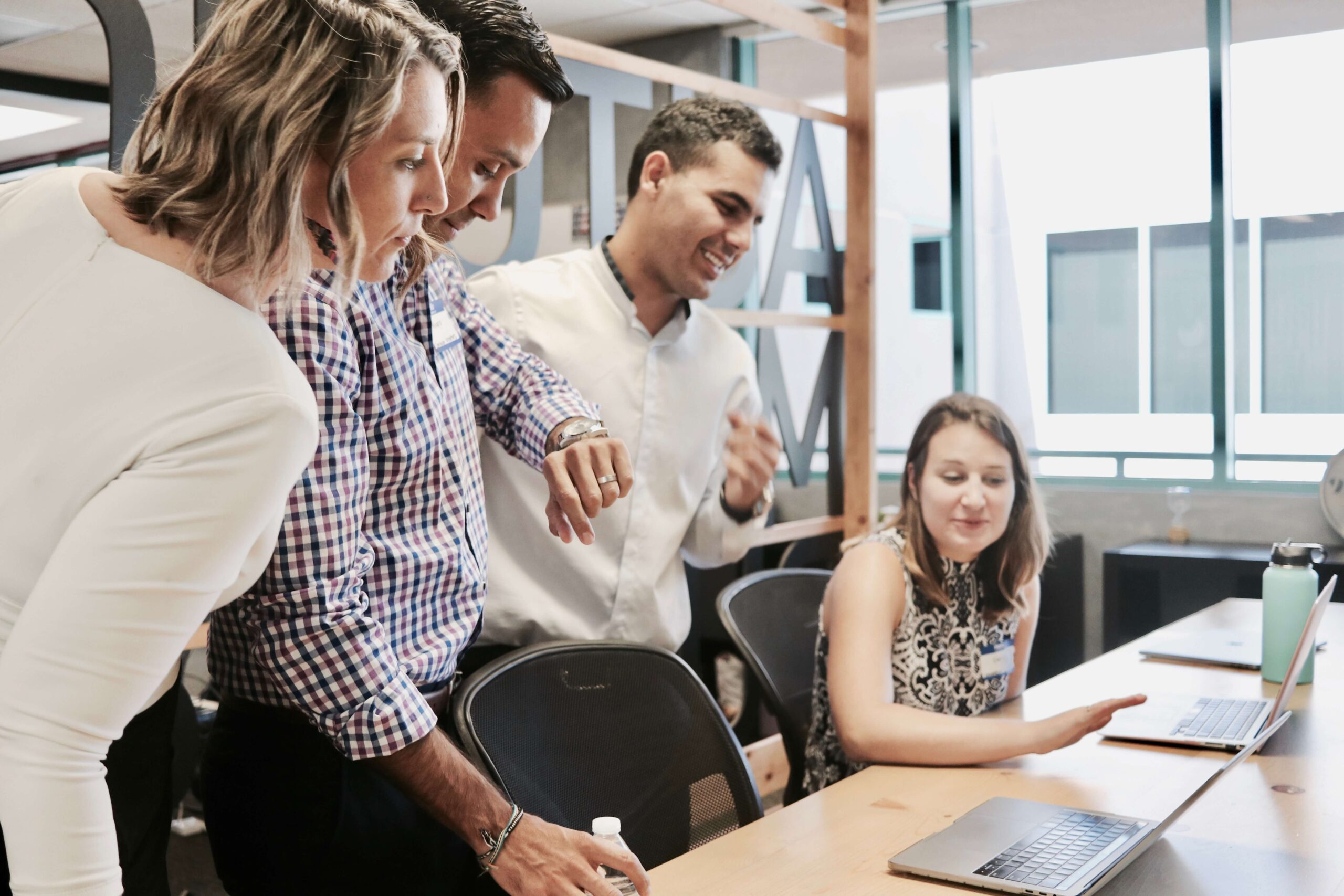 A team of people at work looking over at a coworker's work