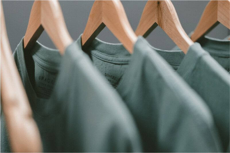 A close up image of powder blue shirts on wooden hangers